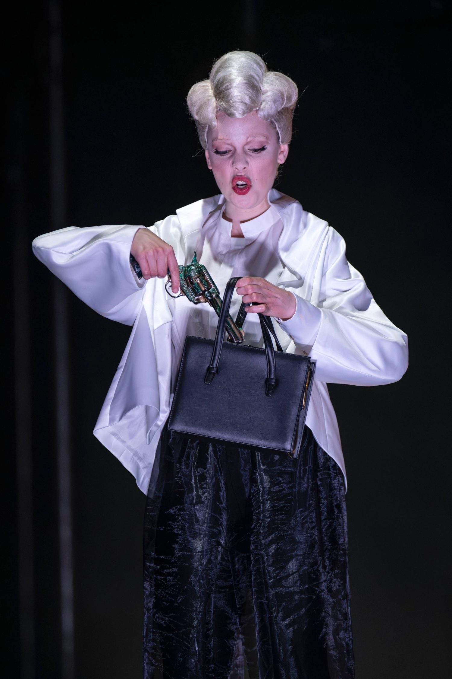 Alexandra Yangel lifting a glittering revolver out of her handbag