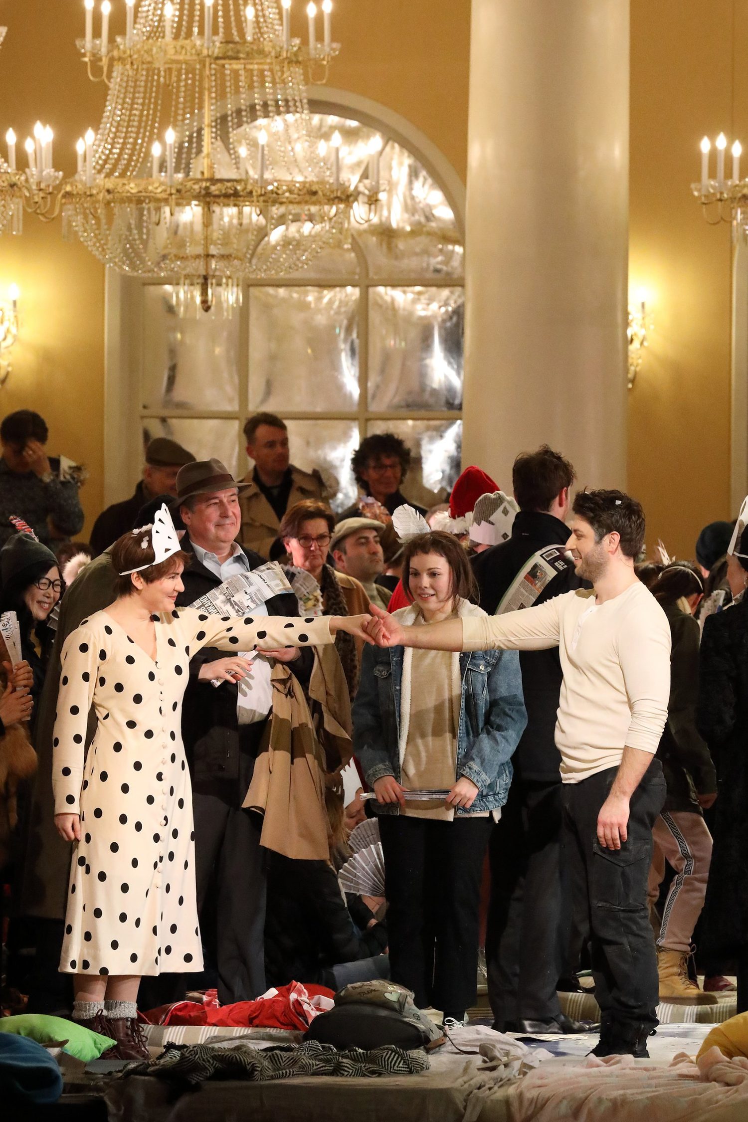 Alexandra Yangel watching in a crowded ballroom as two singers join hands beneath a chandelier
