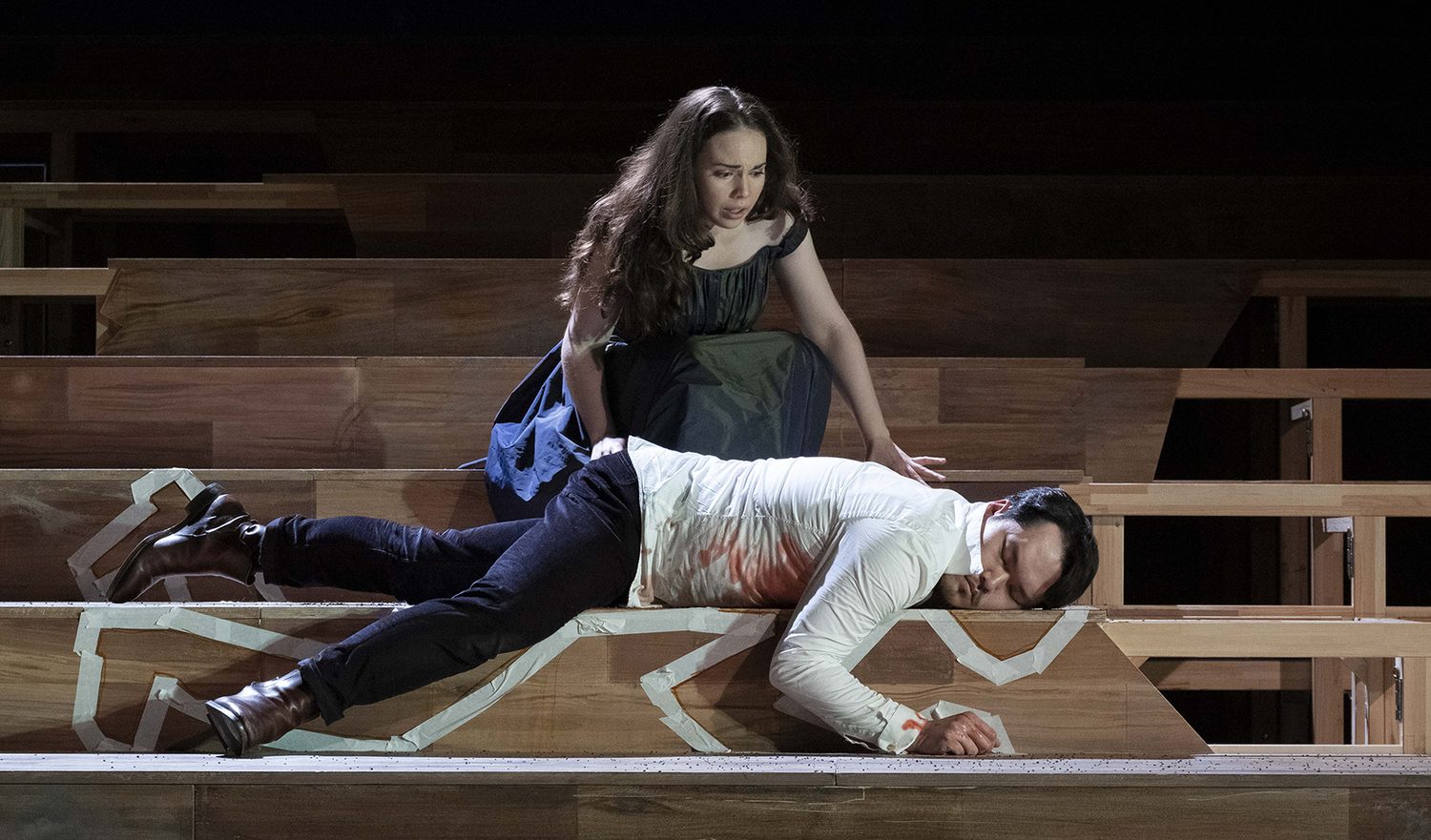 Alexandra Yangel kneeling over a wounded man lying across wooden steps